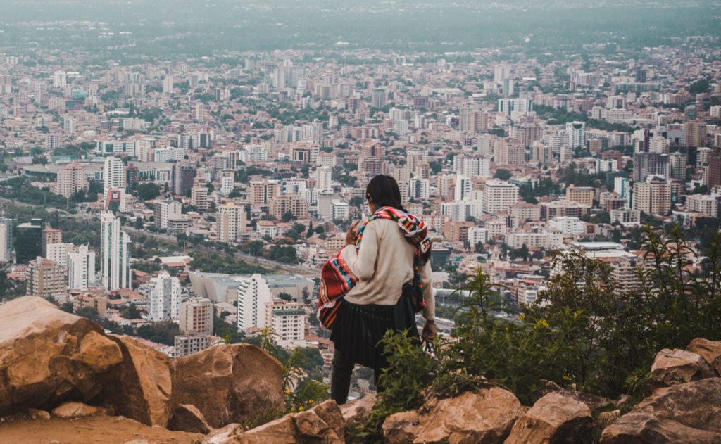 what to pack for travel photography cochabamba city cityscape bolivia development indigenous woman stands on cliff