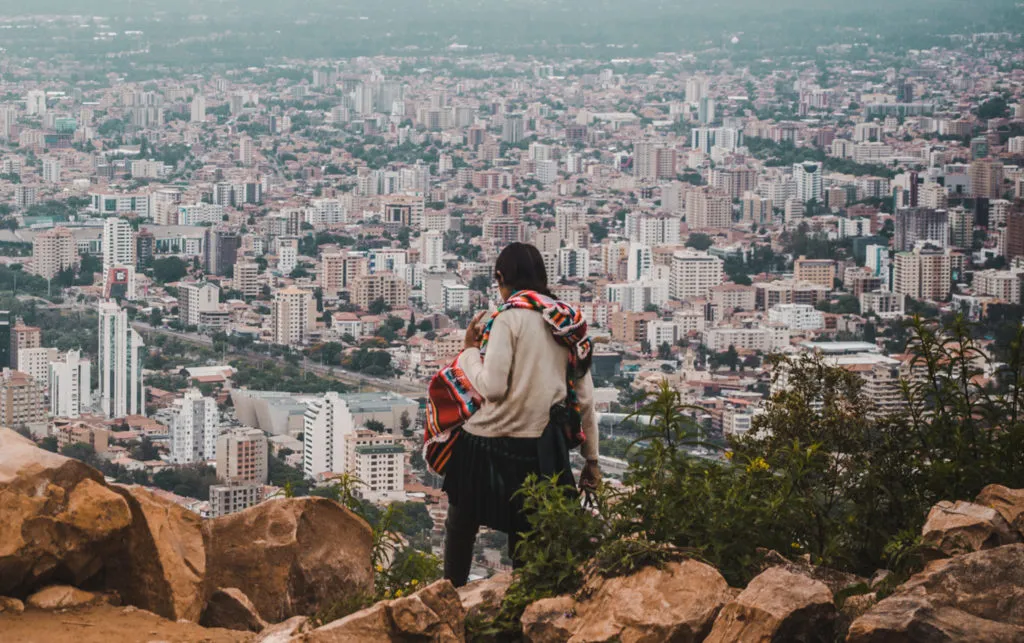 what to pack for travel photography cochabamba city cityscape bolivia development indigenous woman stands on cliff