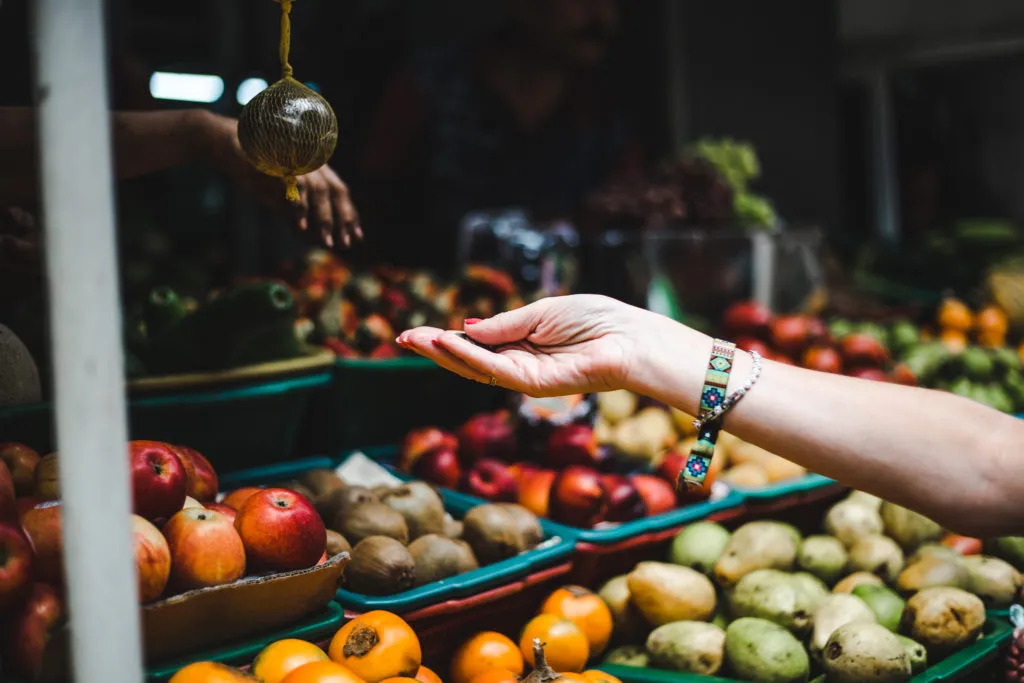 Tourist buying fruit from market stall at Mercado Paloquemao Bogota Colombia